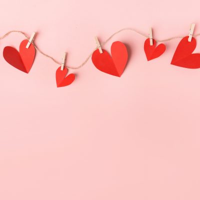 Beautiful valentines day paper hearts hanging on rope on pink background. View from above. Valentines Day Concept.