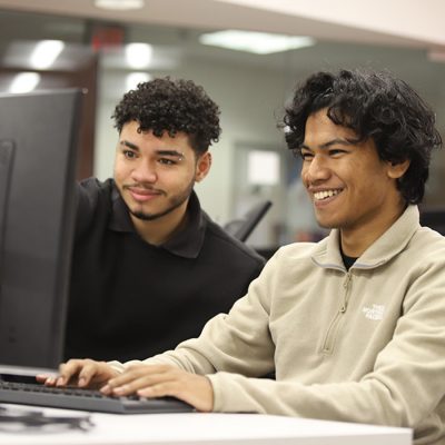 Two male students work together at a computer