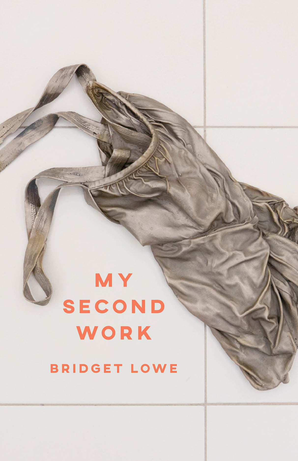 A cover showing a wrinkled, worn gray garment laid on light tile, with orange text.