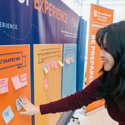 Campus experiential learning display with colorful panels and sticky notes as a participant adds feedback
