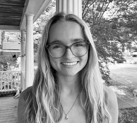A student smiles while posing for a headshot outside in front of a column.