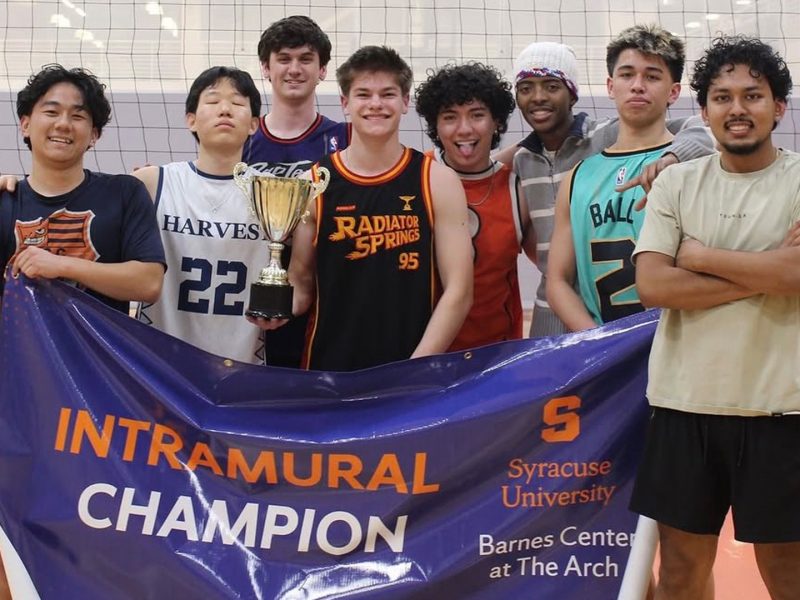Intramural sports team holding a championship trophy and “Intramural Champion” banner inside a gymnasium