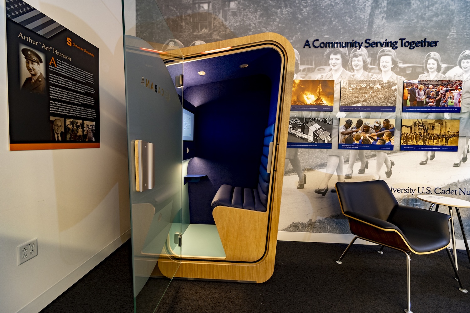 Open cabana pod with cushioned seating, set inside a lobby featuring a historical mural and adjacent lounge chairs.