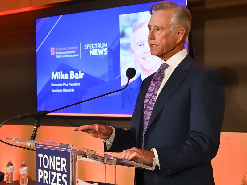 Guest speaker at the Toner Prizes ceremony delivers remarks at a podium on a lit stage