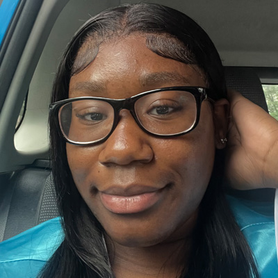 A person takes a selfie wearing glasses and a blue top.