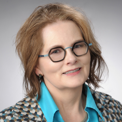 A professor smiles while posing for a headshot indoors.