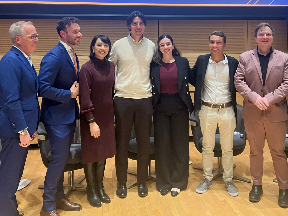 Group of event speakers and organizers standing together on a stage after a panel discussion.