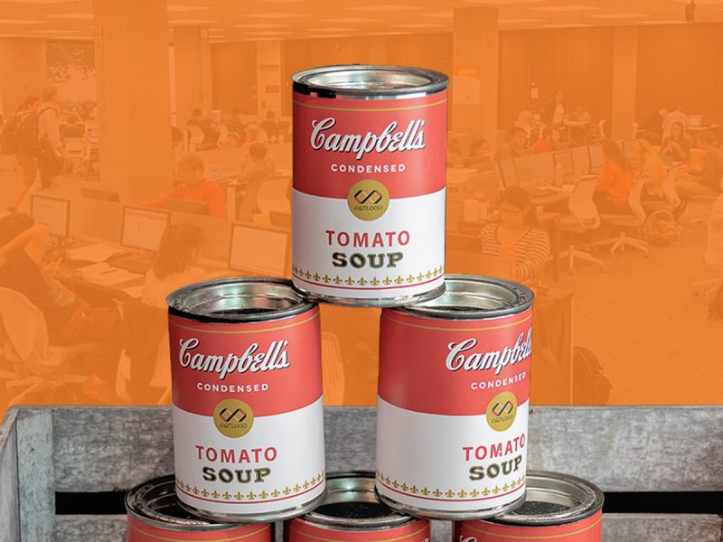 Stack of Campbell’s condensed tomato soup cans arranged in a pyramid against an orange background.