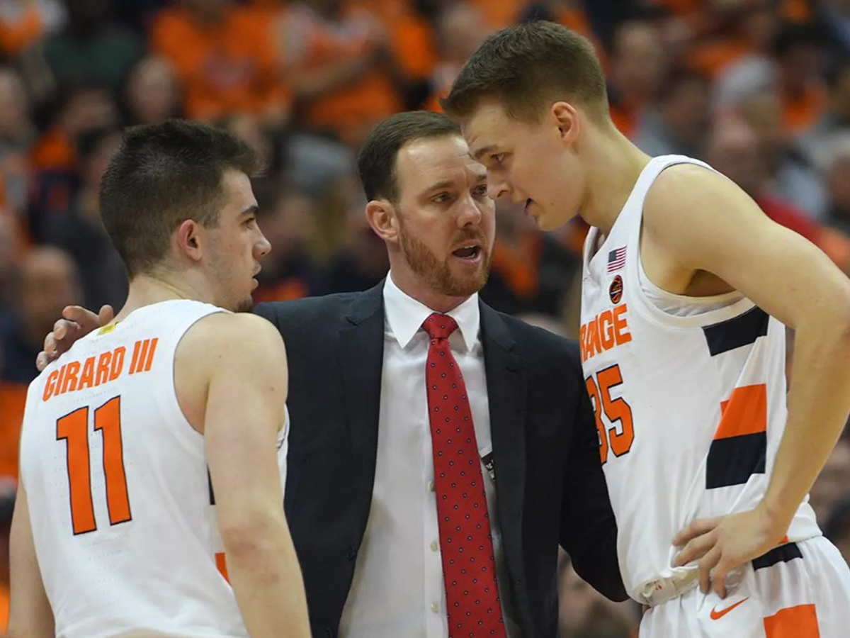 An assistant coach talks with two of his players.