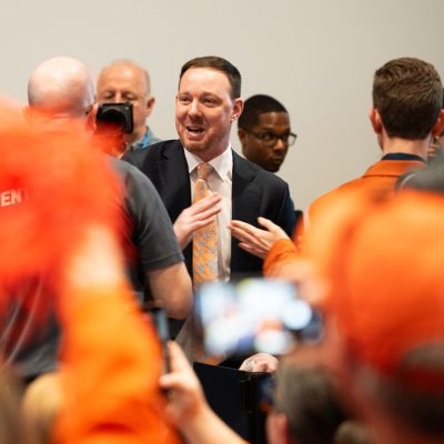 A person dressed in a suit mingles with fans.