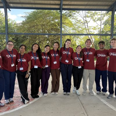 Members of Syracuse University's Global Medical Brigades pose together outdoors in Panama in matching red shirts.