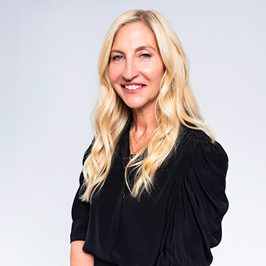 A person smiles while posing for a headshot in front of a white background.