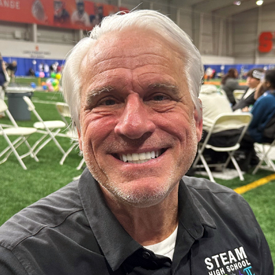 A person smiles while posing for a headshot seated at a table.
