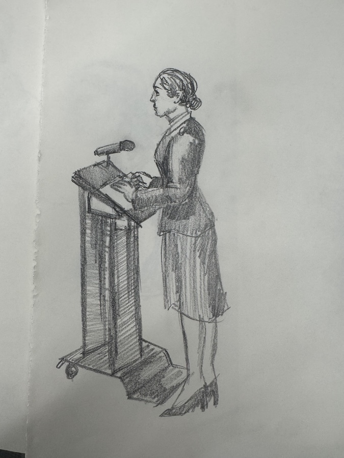Pencil sketch of a person standing at a podium, viewed from the side, delivering remarks.