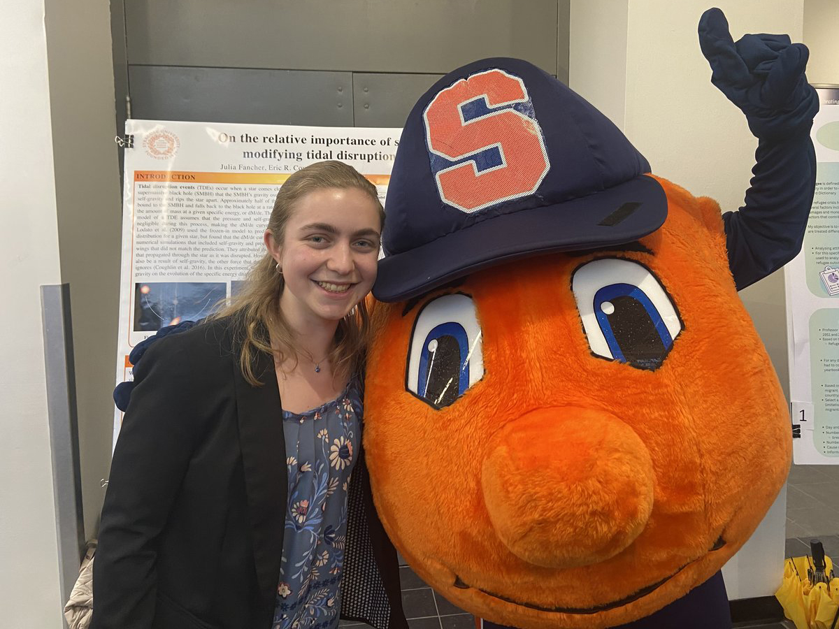 A smiling student poses with Otto the Orange mascot in front of a research poster on tidal disruption events.