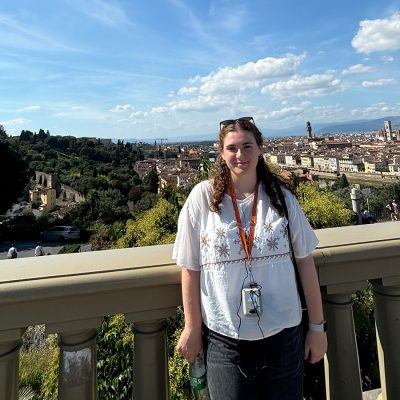 A student poses at the Piazzale Michelangelo in Florence. The Duomo and Palazzo Vecchio are perfectly framed in the background.