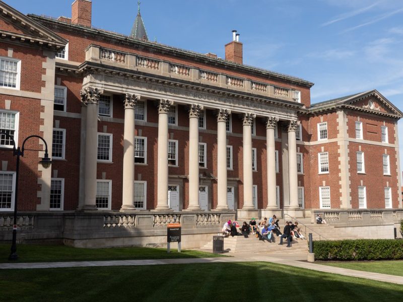 Students sit on the steps of Maxwell Hall, home of the Maxwell School of Citizenship and Public Affairs.