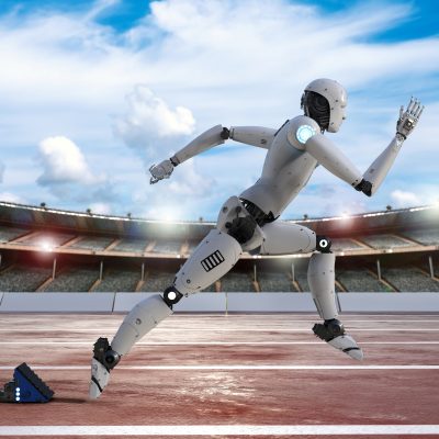 A computer-generated illustration of a white humanoid robot in a running stride on a red track, with starting blocks visible in the background and a stadium crowd under a partly cloudy sky.