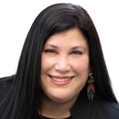A person smiles in a professional headshot wearing a black top and beaded earrings against a white background.