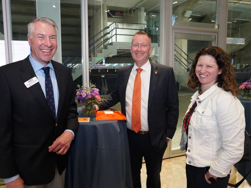 David Van Slyke, Mike Haynie and Shana Gadarian stand together smiling at a cocktail table during a research celebration event at Syracuse University.