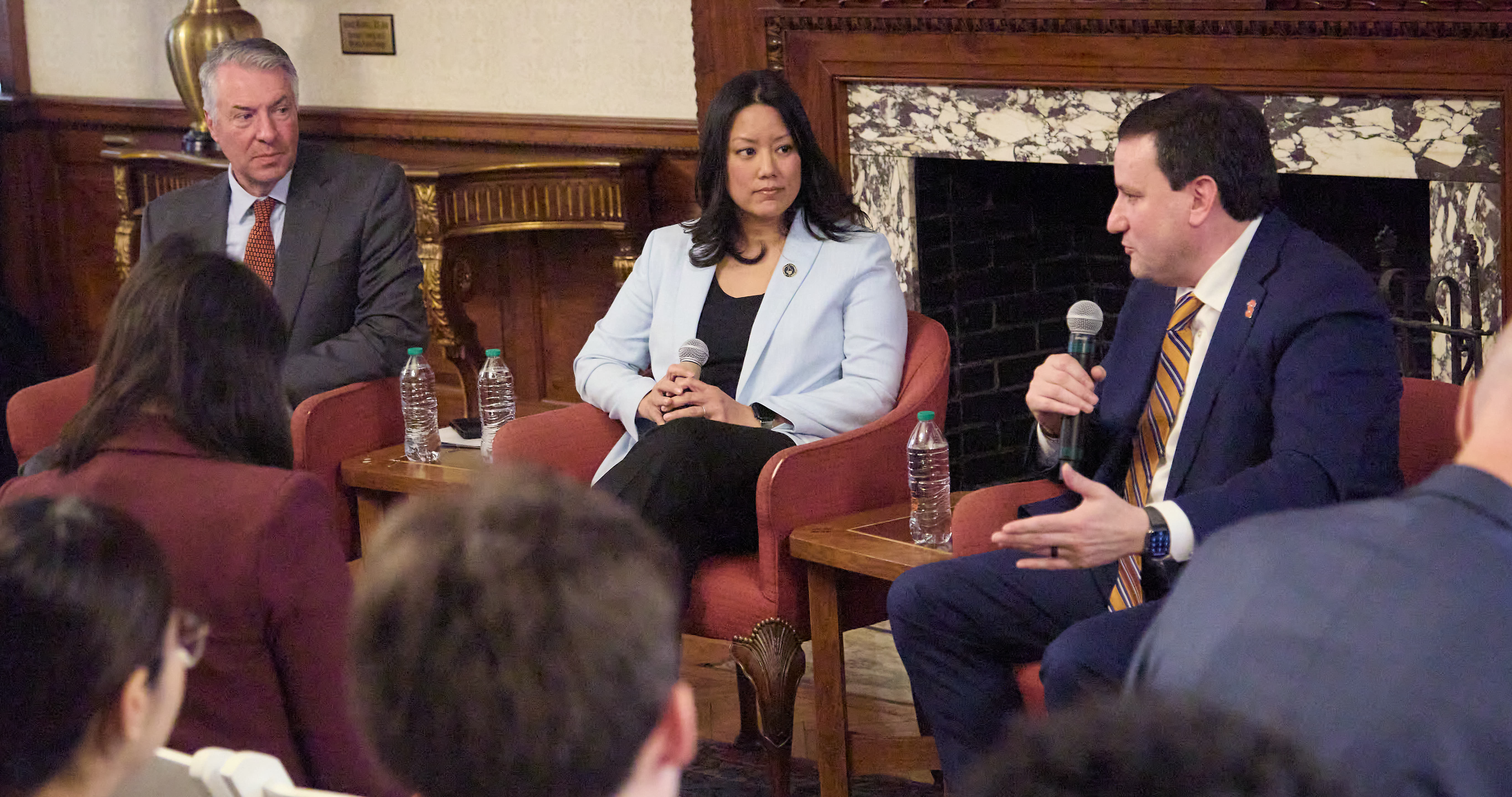 Three panelists participating in a moderated discussion, with an audience visible in the foreground.