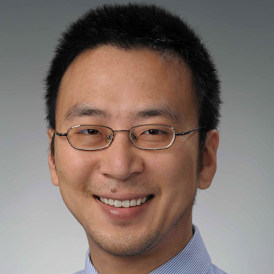 A man wearing glasses, smiles in a headshot photo.