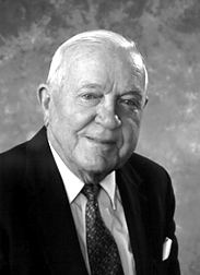Man with white hair wearing a suit and tie.