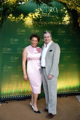 "Two attendees smile together on the step-and-repeat backdrop at the American Academy in Rome's McKim Medal Gala 20th anniversary event."