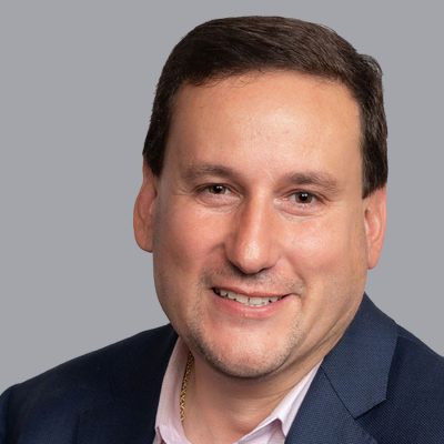 A professor smiles while posing for a studio headshot.