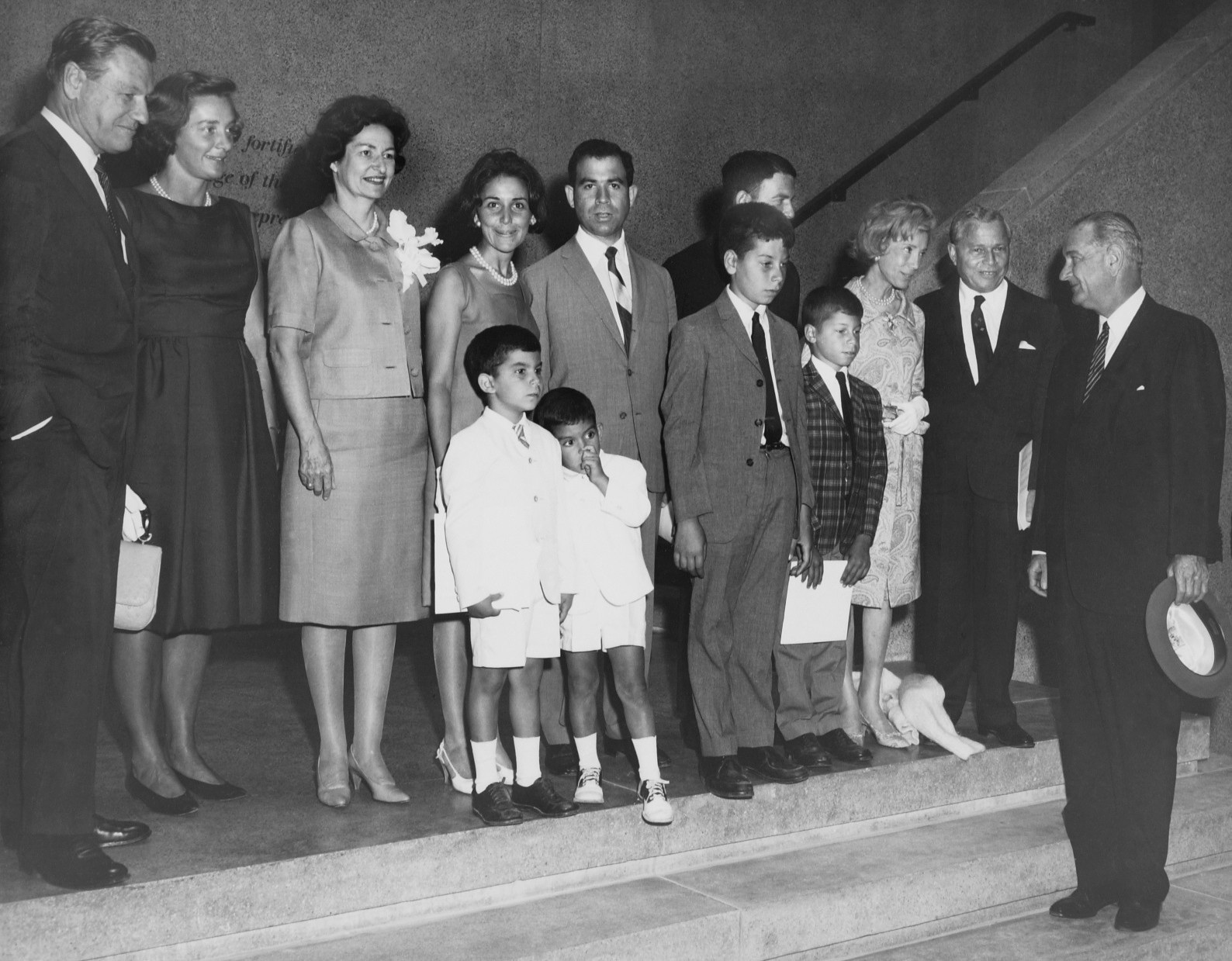 A group of adults and children standing on the steps inside the S.I. Newhouse School of Public Communications
