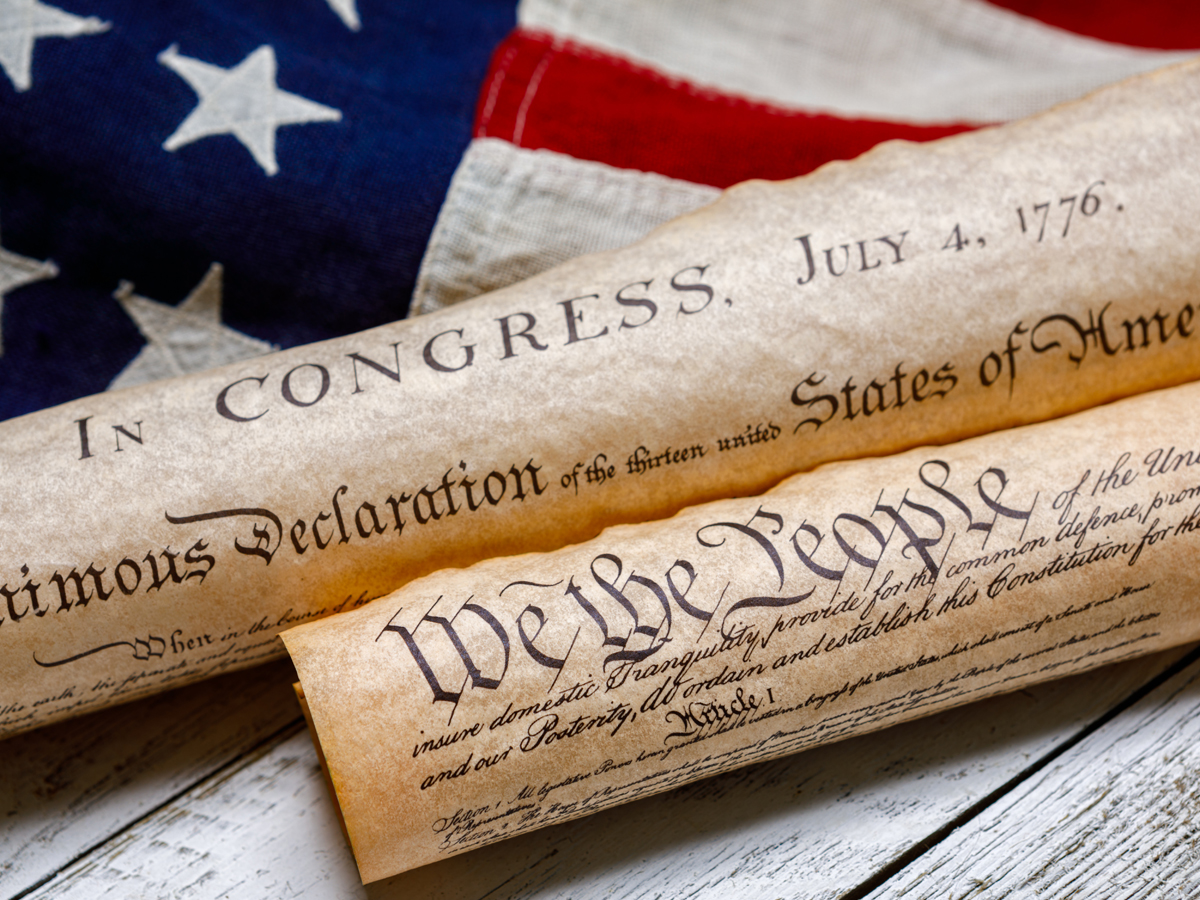 Rolled scrolls of the Declaration of Independence and Constitution on an American flag