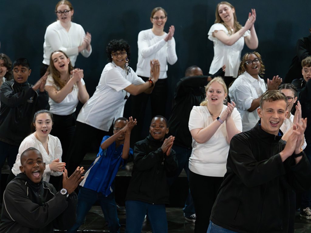 Members of the Hendricks Chapel Choir, in white shirts, clap and sing alongside young students from the Drakensberg Boys' Choir during a joint workshop in Pietermaritzburg, South Africa.