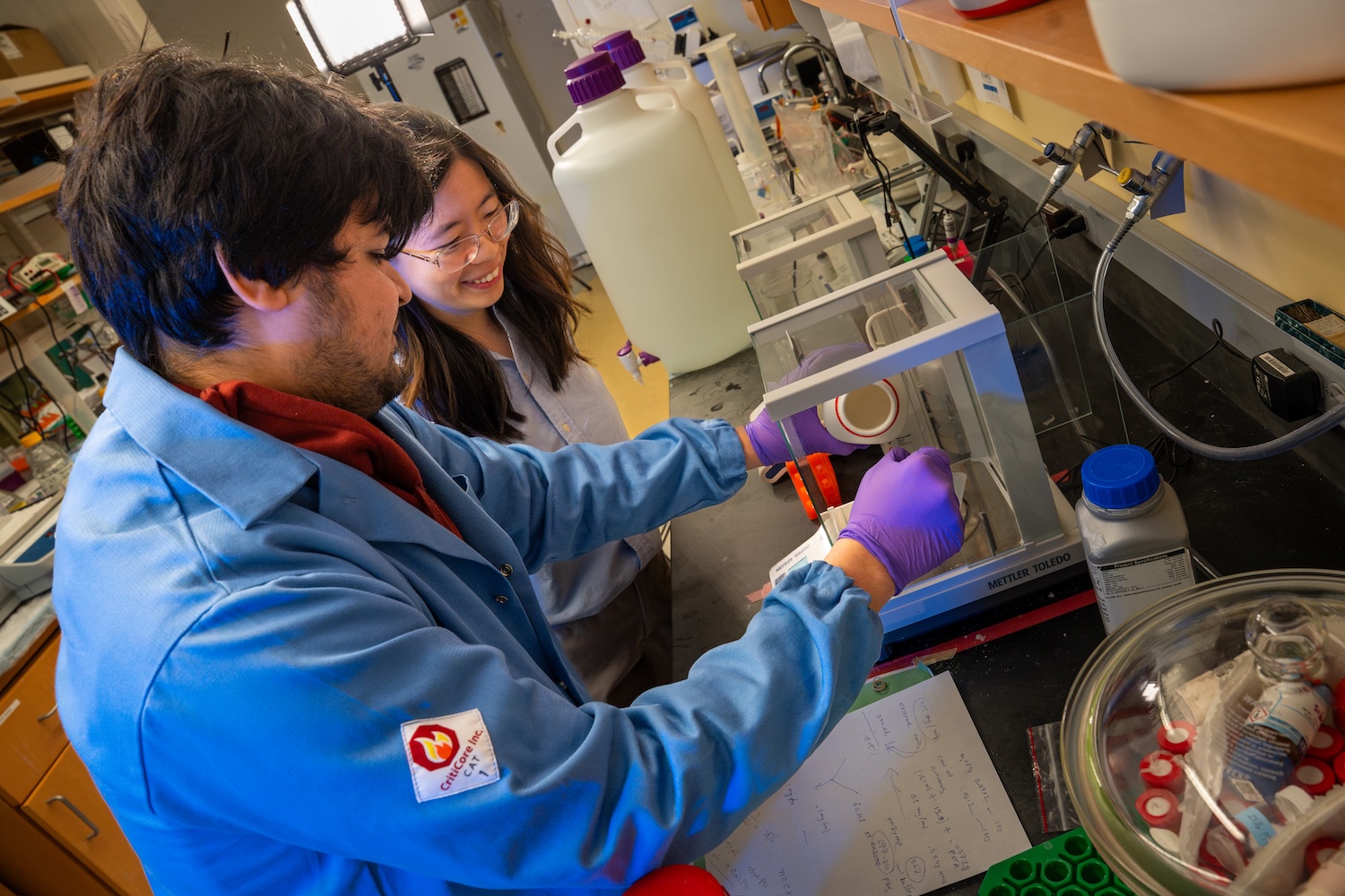 Two people in lab coats using scientific equipment in a laboratory.