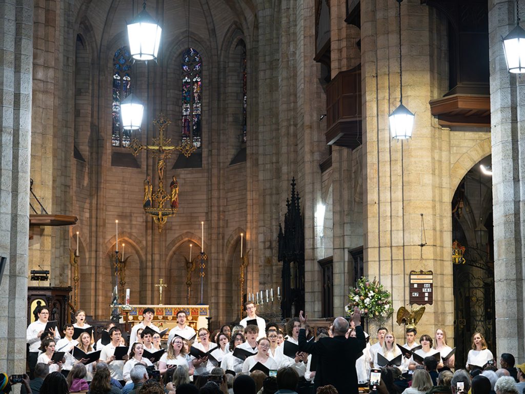 The Hendricks Chapel Choir performs in St. George's Cathedral in Cape Town, South Africa, with director José "Peppie" Calvar conducting beneath the cathedral's soaring Gothic stone arches and stained glass windows.