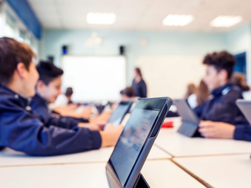 students work on tablets at their desks during class