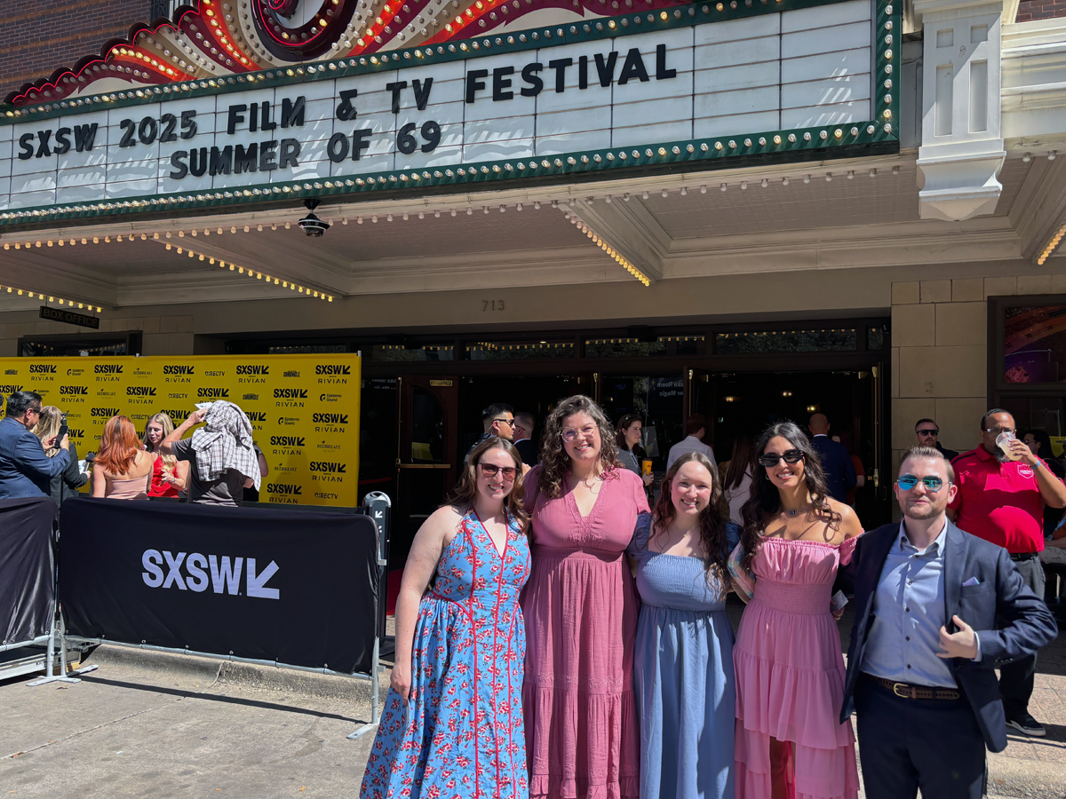 A group of five people pose together outside a theater under a marquee reading "SXSW 2025 Film & TV Festival, Summer of 69," with SXSW-branded step-and-repeat signage and barricades visible behind them.