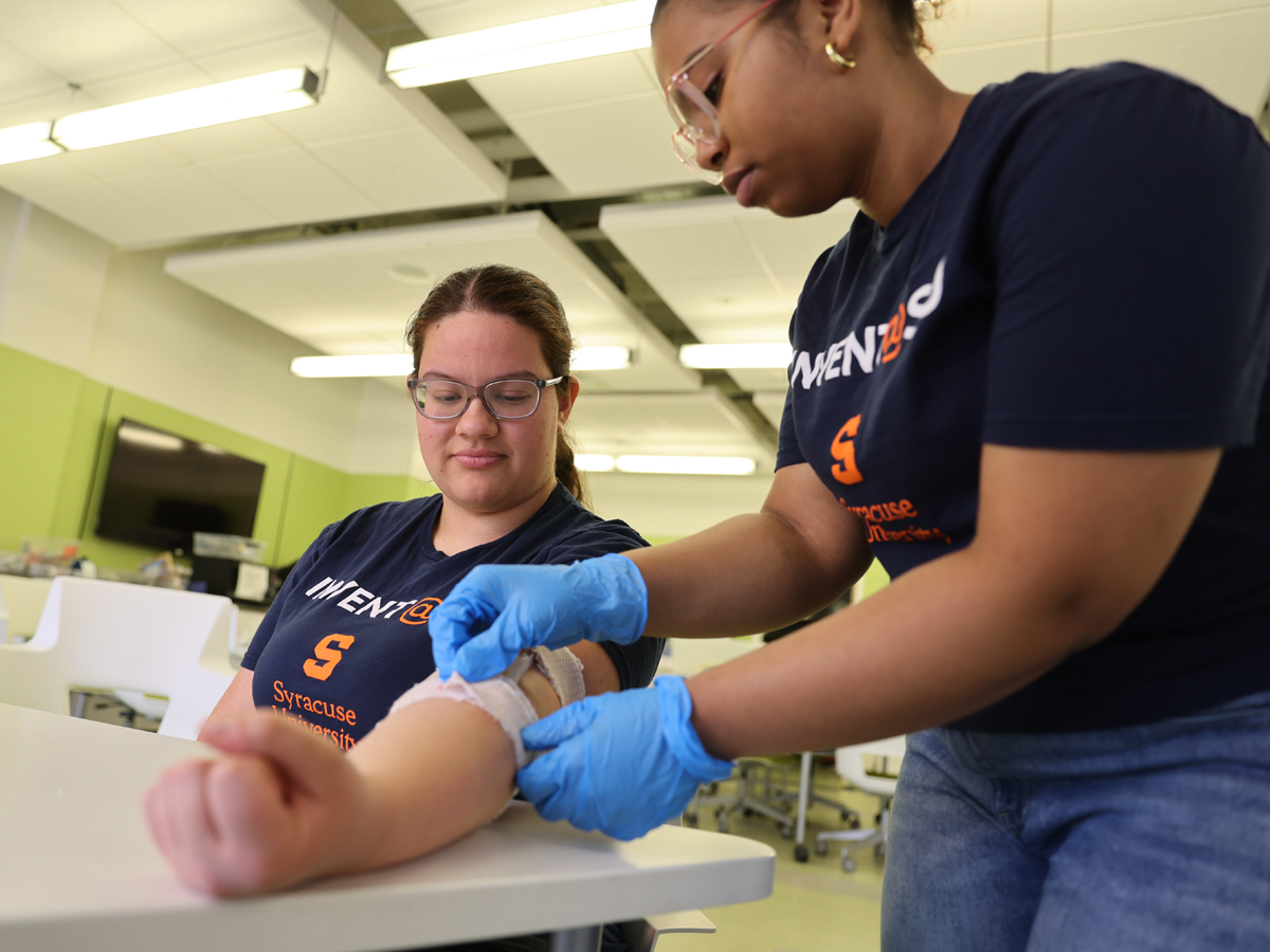 An Invent@SU student wraps a bandage-like device around another student's arm.