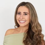Professional headshot of Dana Casullo, a woman with long wavy brown hair, smiling, wearing an off-the-shoulder sage green top against a white background.