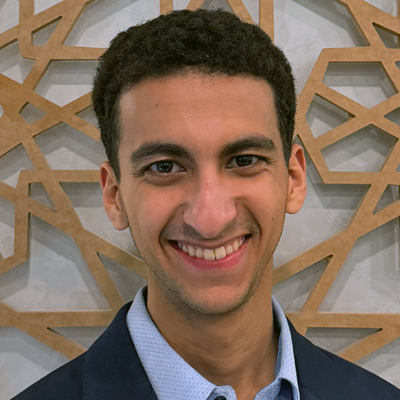 Headshot of Elyas Layachi smiling against a geometric patterned background
