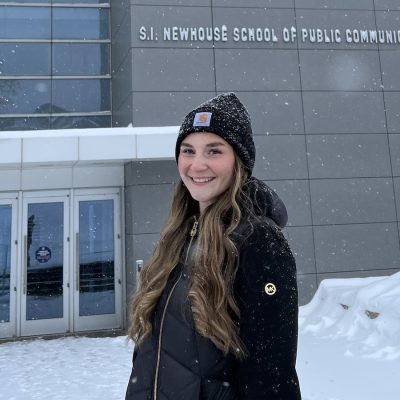 Person standing outside the S.I. Newhouse School of Public Communications during a snowy winter day.