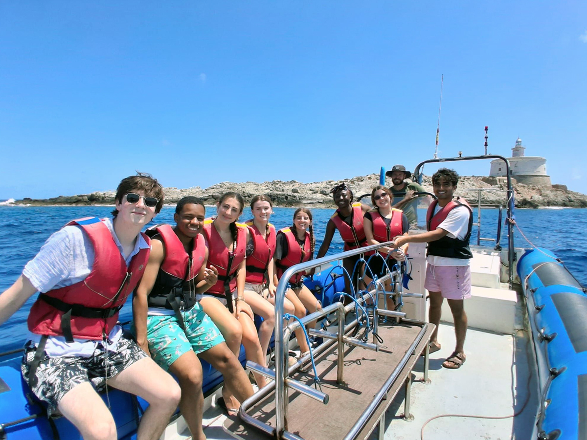Students in life vests on a boat during a marine ecology course excursion at sea.