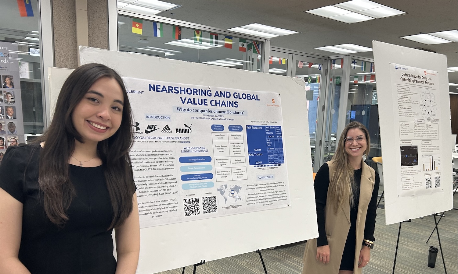Two students standing beside research posters at an academic poster presentation event.