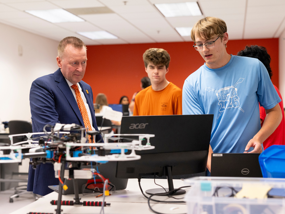 Chancellor Haynie views a drone with students at Orange Works.