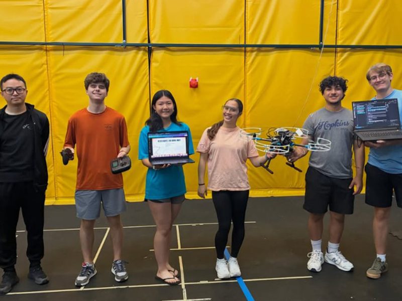 Students hold a drone, laptops and controllers in Orange Works.