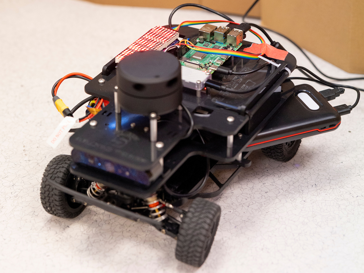 A student-built autonomous race car with exposed circuitry and sensors.