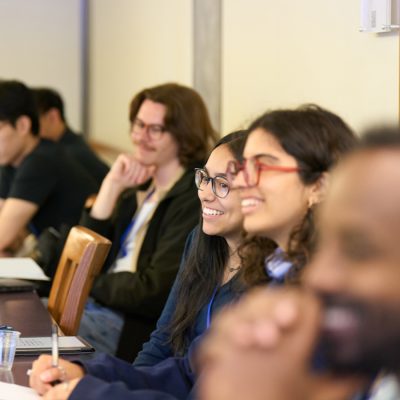 Five researchers seated in a row at a table, two smiling during a talk