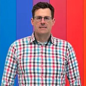 A person poses in front of a brightly lit backdrop.