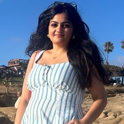 A person smiles with palm trees in the background