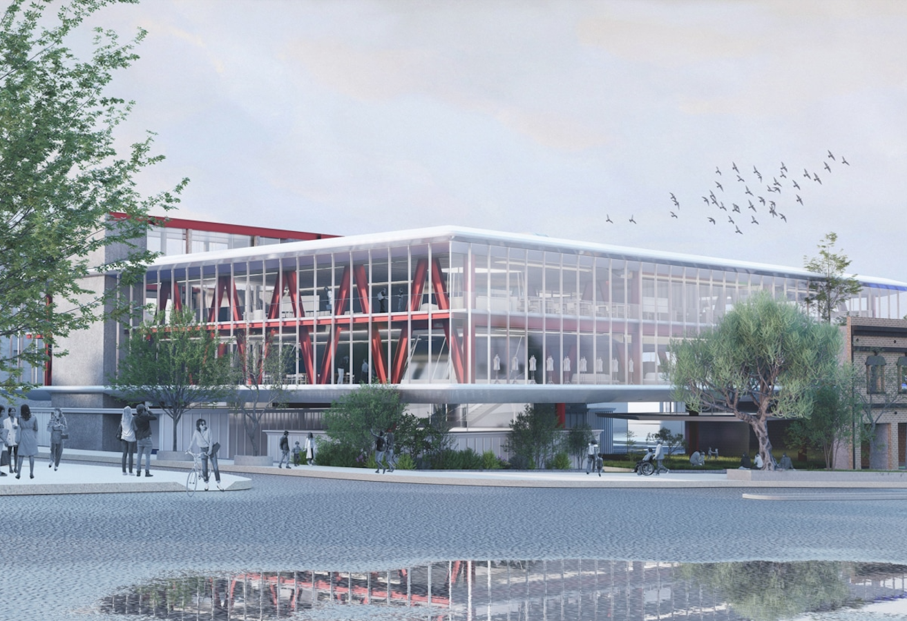 Modern glass-and-steel building with red structural supports, surrounded by trees and pedestrians beside a reflective water feature.