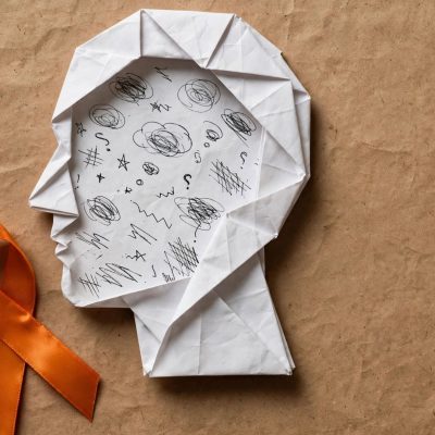 Paper head silhouette with an orange ribbon, representing ADHD awareness month